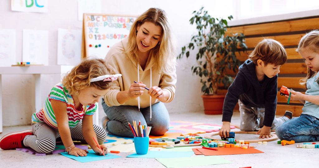 Teacher and nursery kids playing and looking happy