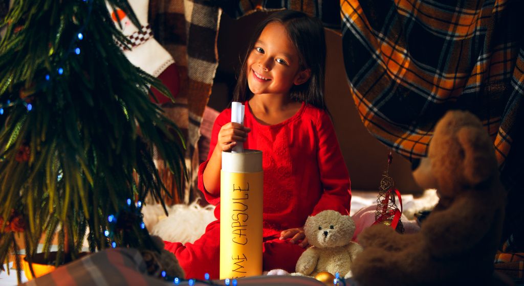 young girl making a time capsule and smiling at the camera with joy