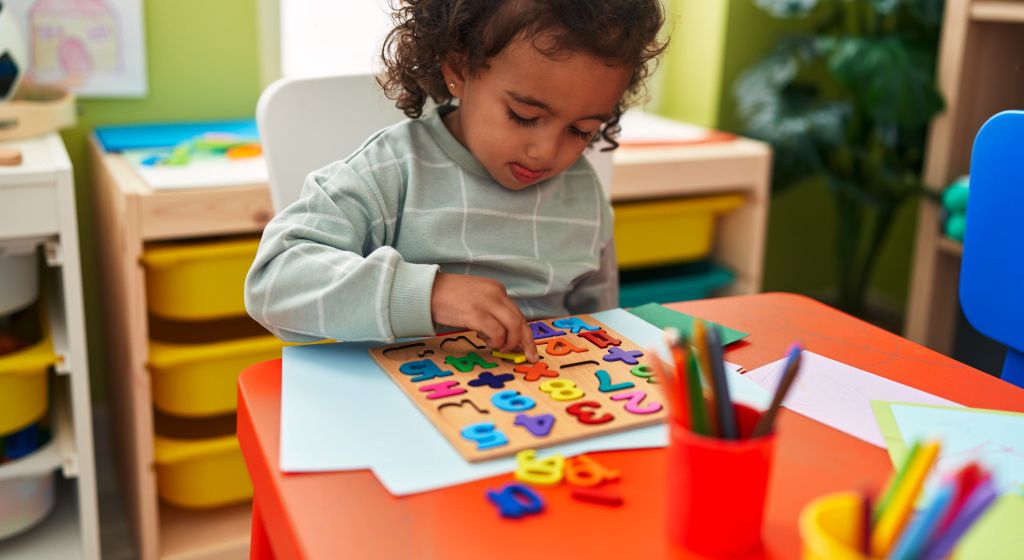 Young girl doing an educational puzzle at nursery