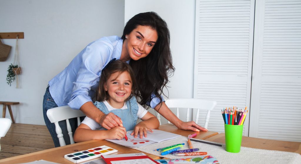 woman smiling with kid that's drawing
